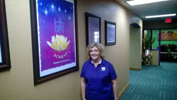 Woman standing in a hallway beside a framed lotus flower poster